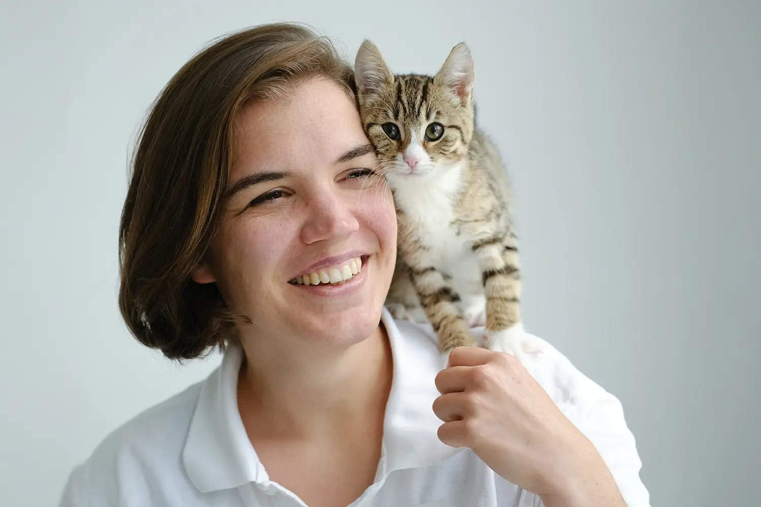 Fröhliche Frau mit einer Katze auf der Schulter